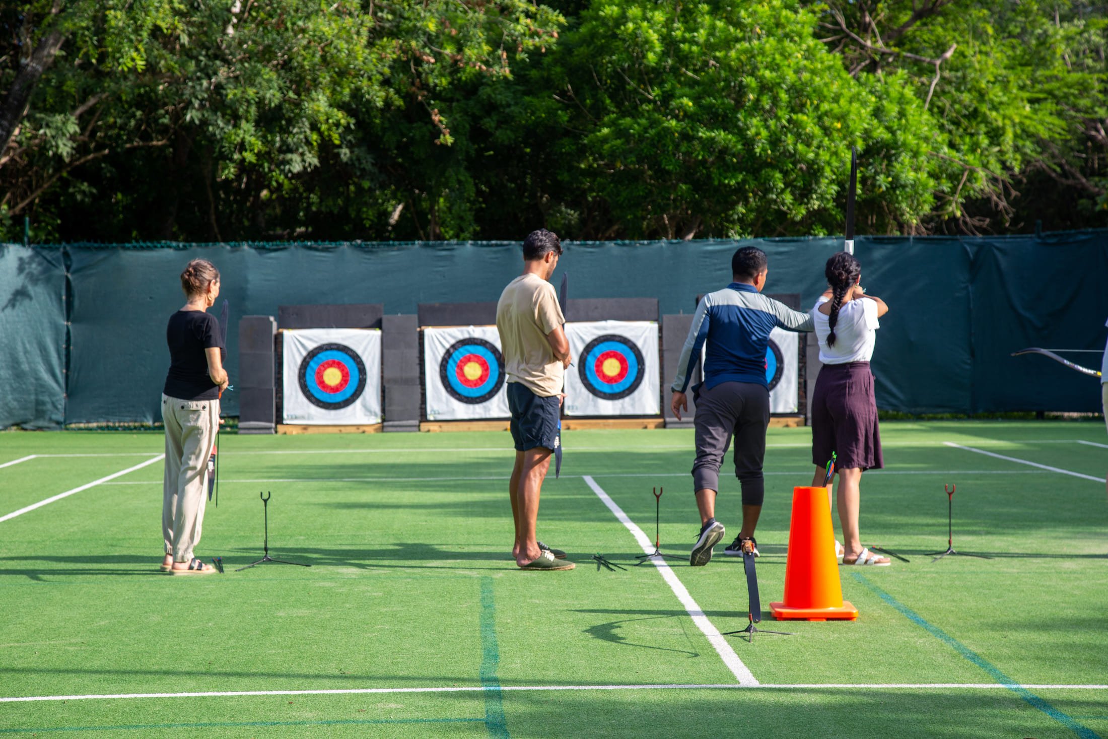 People practicing archery in an outdoor court.