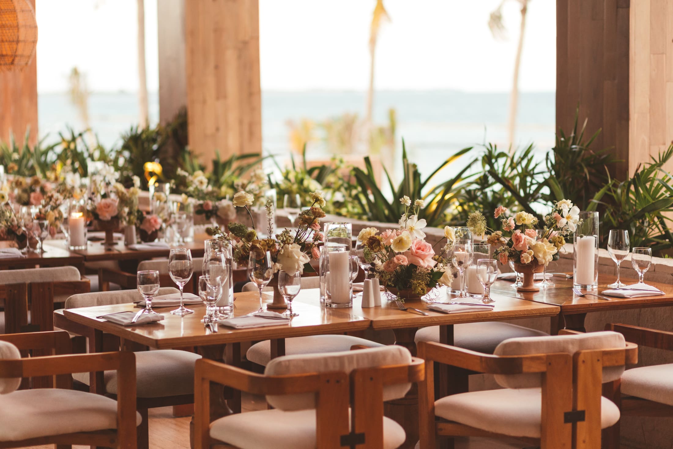 Elegant dining tables set with glassware and flowers.
