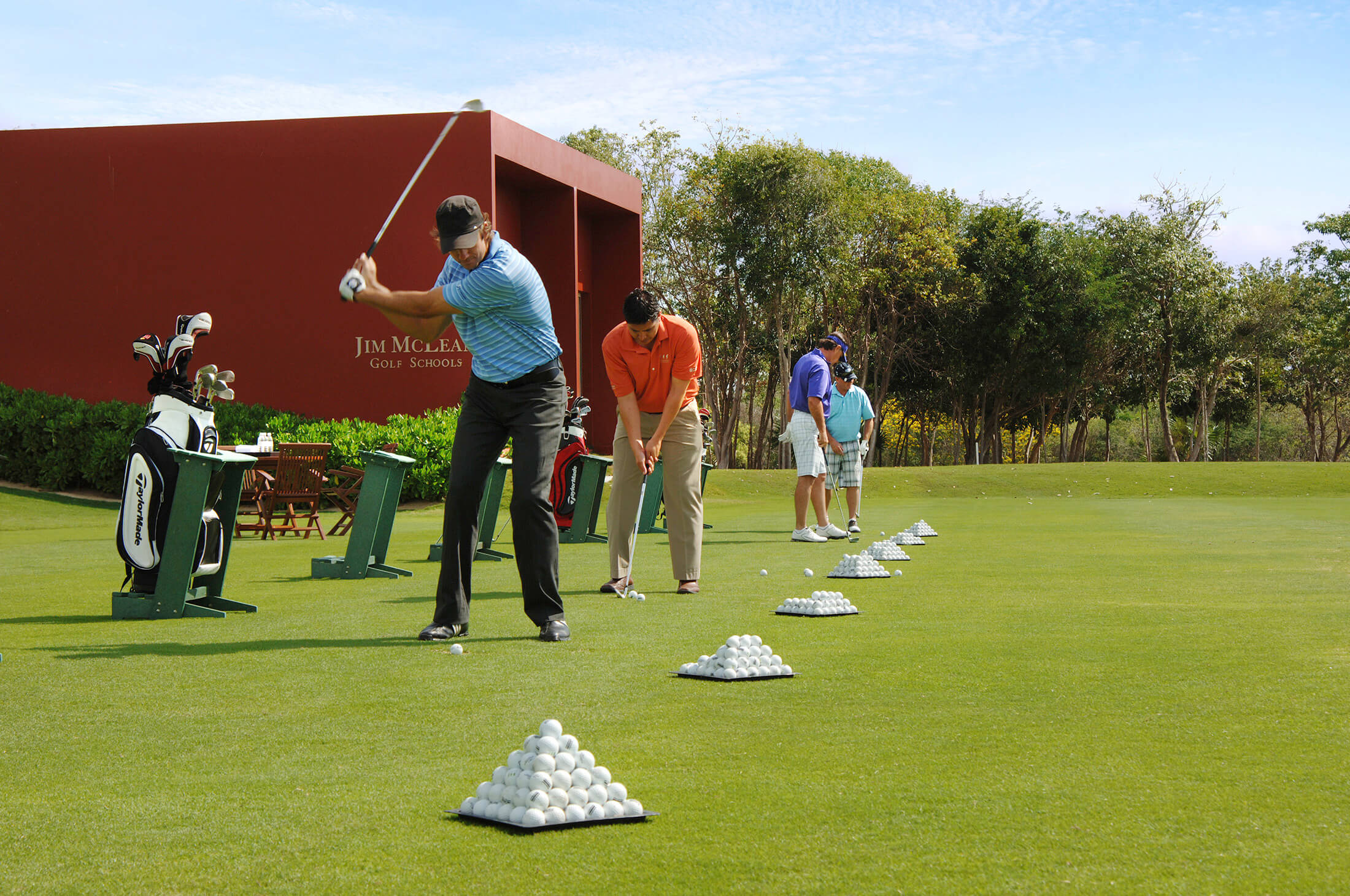 Men in a row at a driving range at the Jim Mclean golf school.