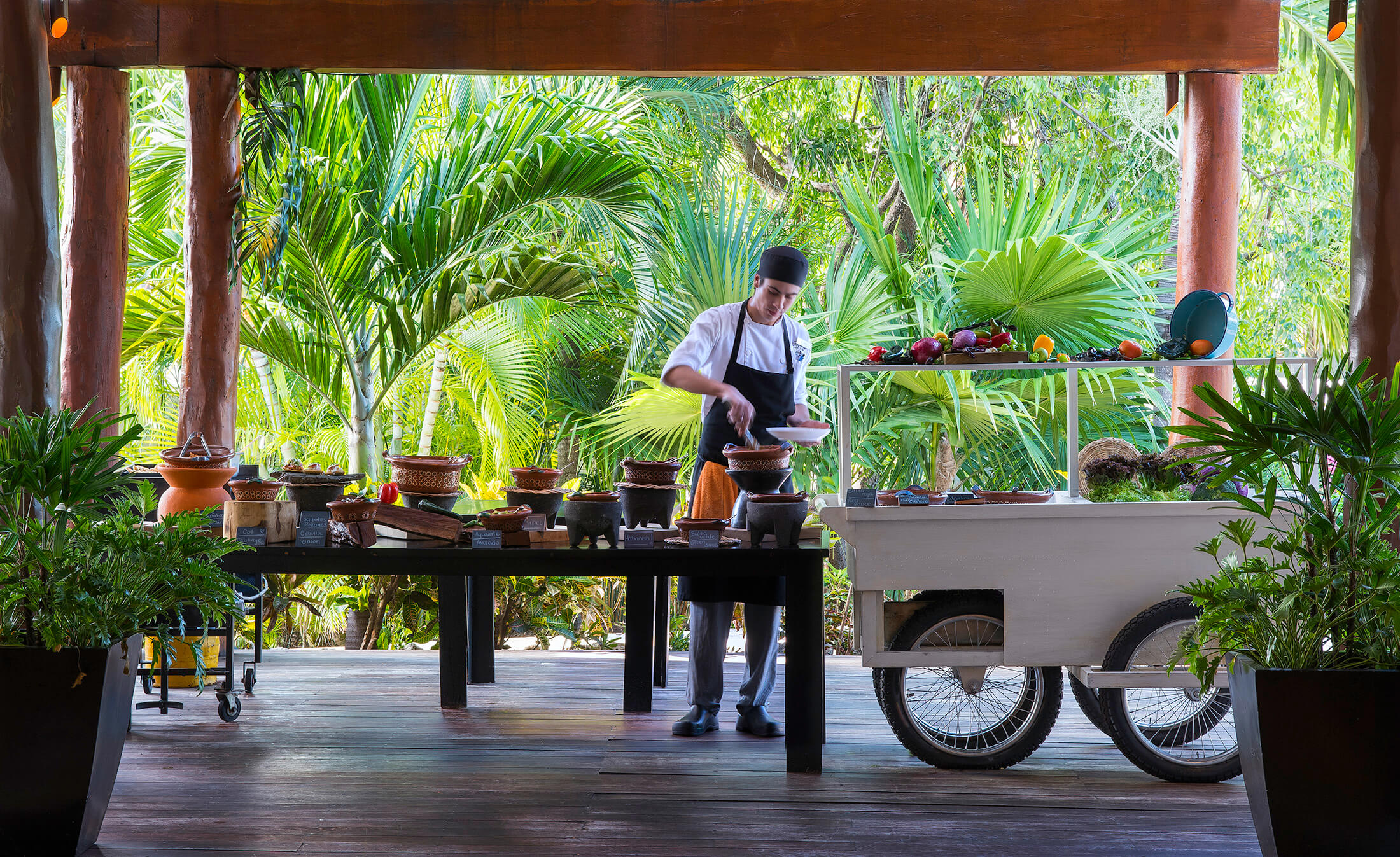 A kitchen worker stocking a food station in an outdoor dining area of Fairmont Mayakoba.