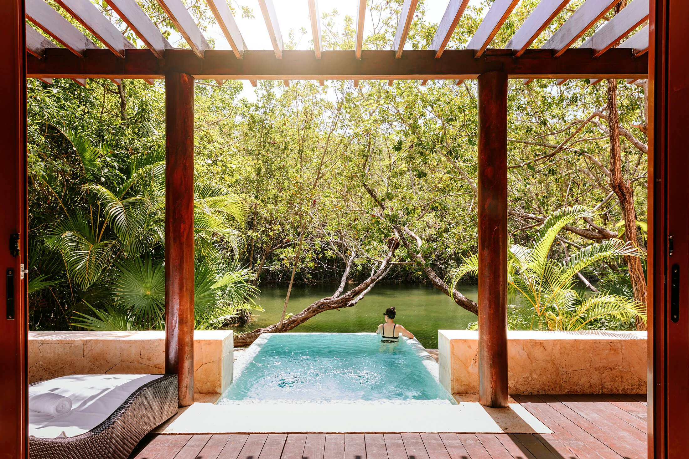 A woman in an infinity pool overlooking a canal at Fairmont Mayakoba hotel.
