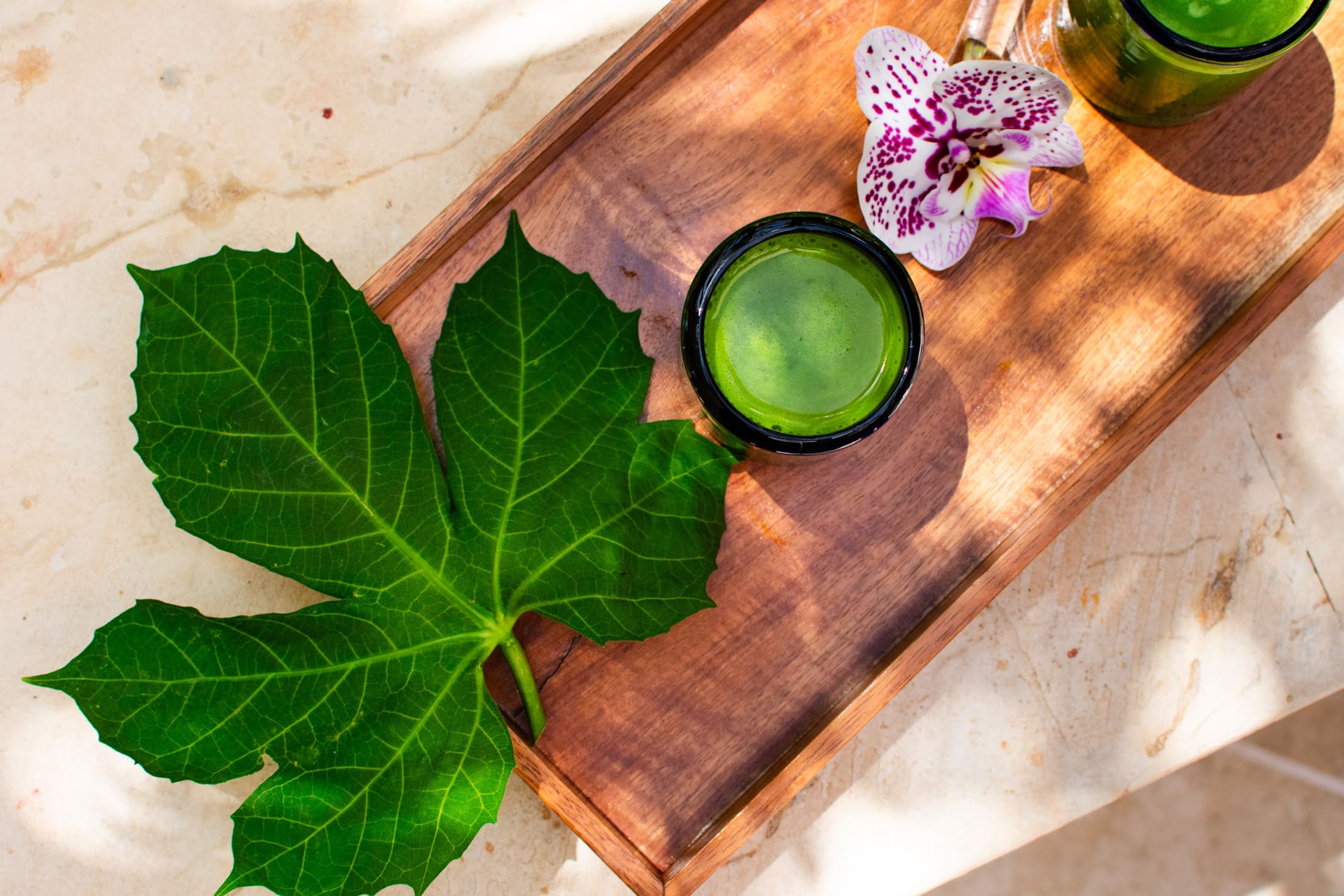 A wooden tray with leaves, candles, and flowers