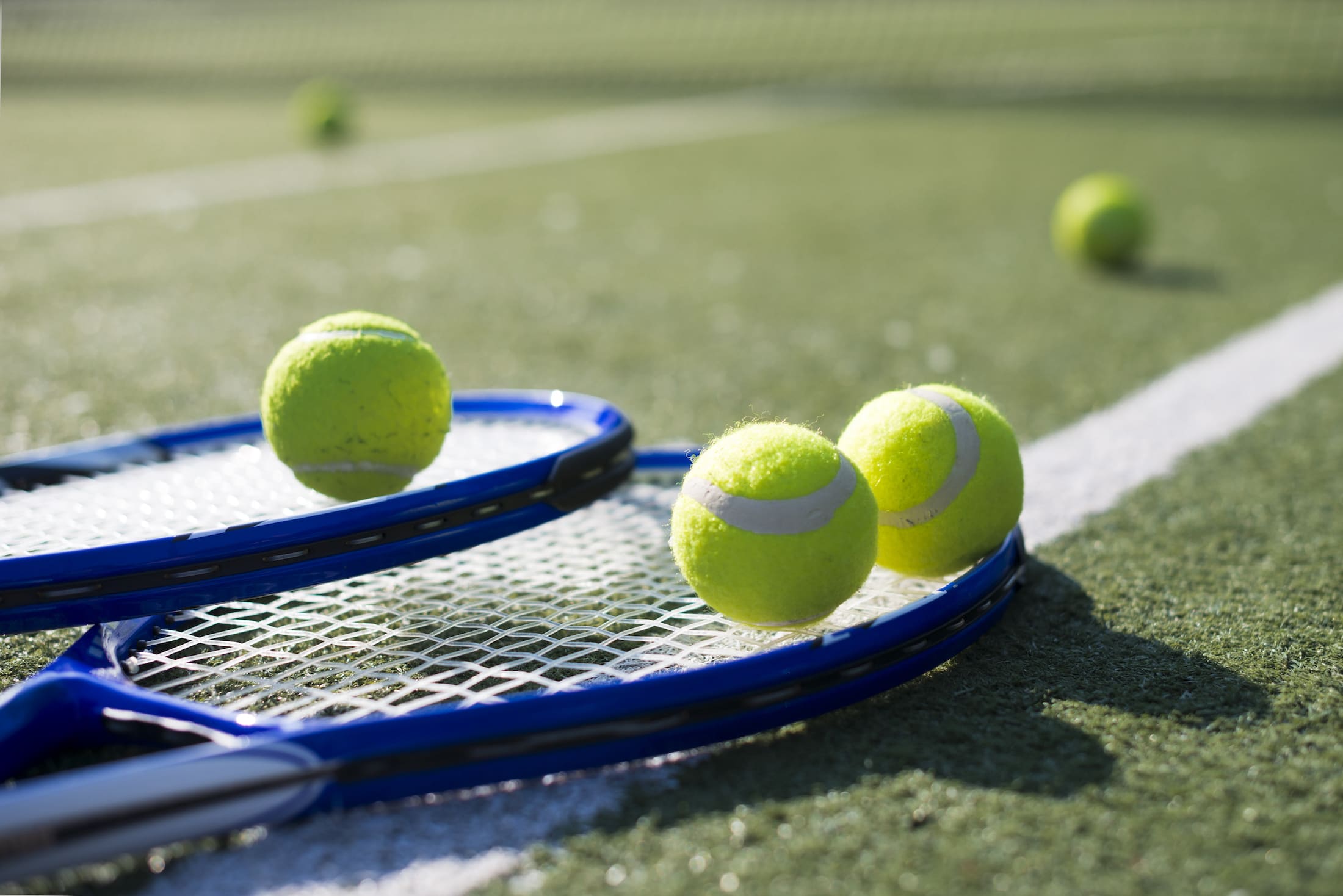Tennis rackets and balls on an astroturf court