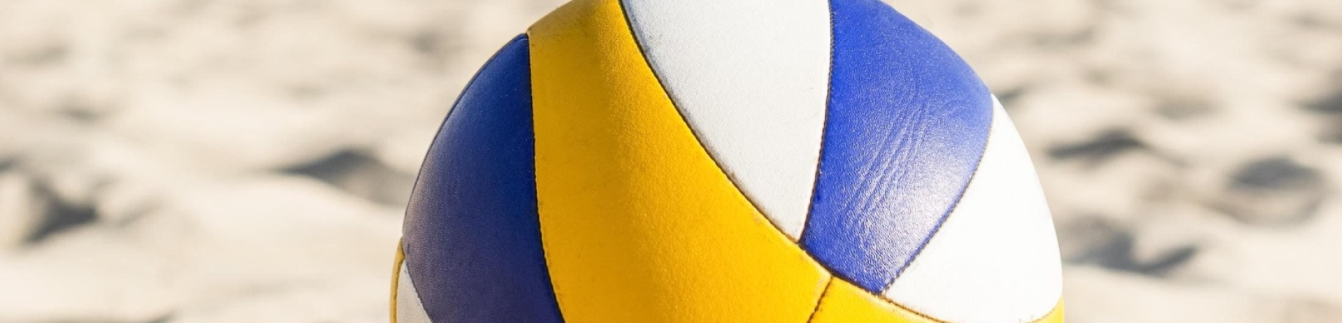 A beach volleyball on sand by a net