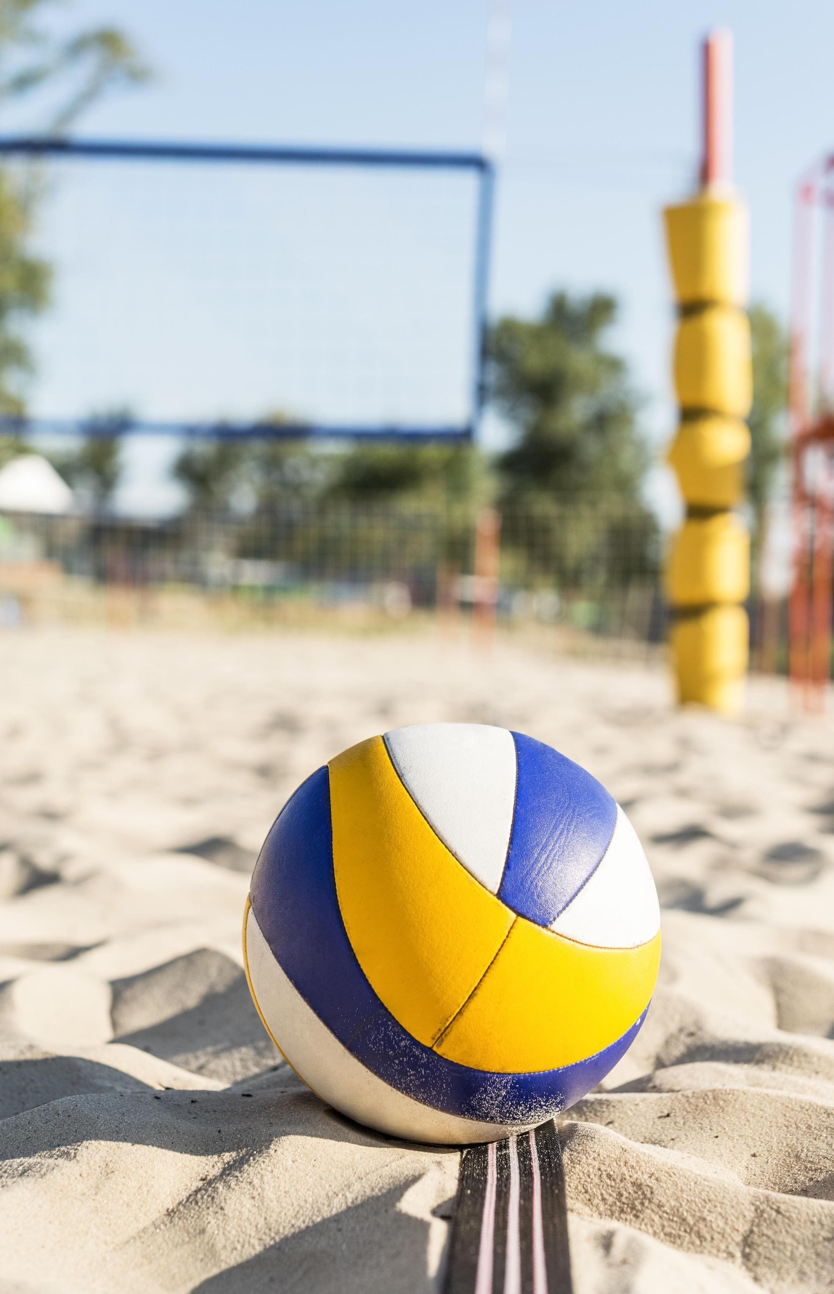 A beach volleyball on sand by a net