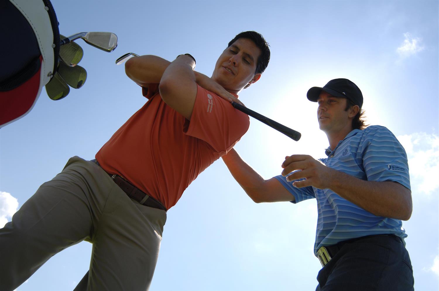 A golf pro coaching a man on a golf course.