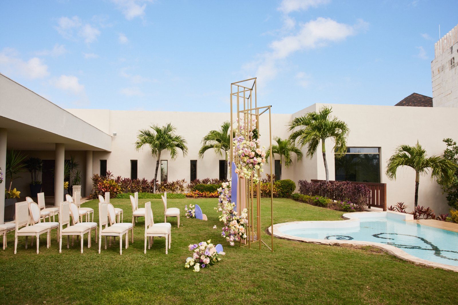 An outdoor wedding ceremony set up on a lawn by an infinity pool