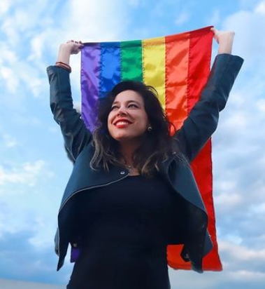 A woman holding a Pride flag over her head.